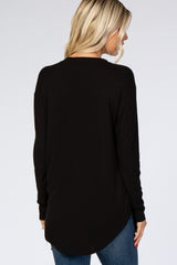 woman wearing a black long sleeve top with a relaxed fit and curved hem, seen from the back