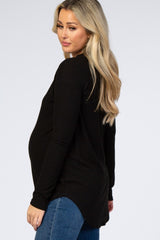 woman wearing a black long sleeve maternity top and showing her baby bump, paired with blue jeans