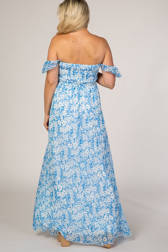 woman wearing a light blue off-the-shoulder floral maternity maxi dress, showing a flowing back view