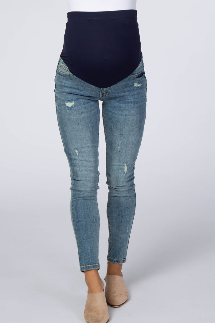 woman wearing a pair of distressed maternity skinny jeans with a navy blue over-the-bump waistband
