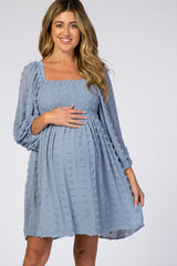 woman wearing a light blue maternity dress with a smocked bodice and puff sleeves, holding her baby bump