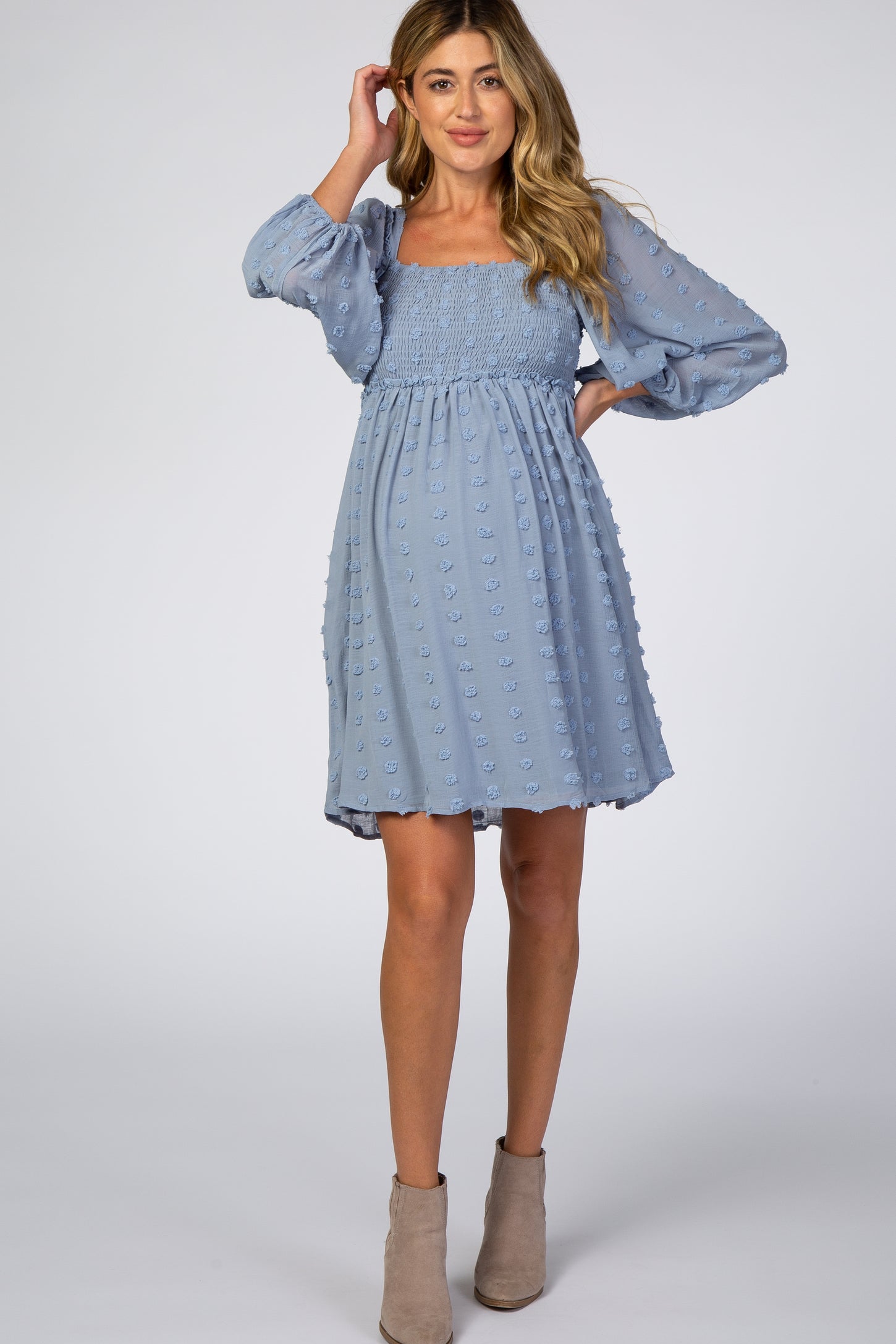 woman wearing a light blue maternity dress with puff sleeves and smocked bodice, highlighting her baby bump