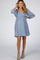 woman wearing a light blue maternity dress with puff sleeves and smocked bodice, highlighting her baby bump