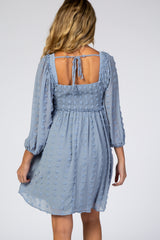 woman wearing a light blue maternity dress with smocked bodice and textured detailing, showing the back view