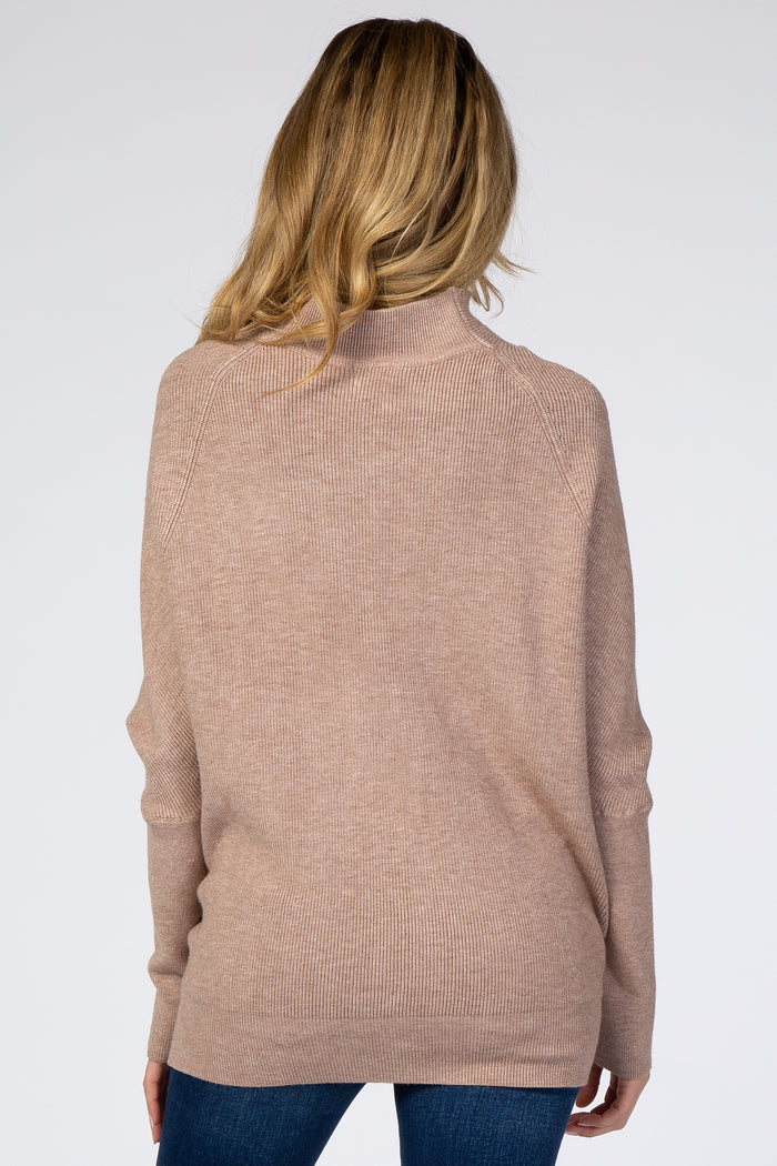 woman wearing a soft beige oversized maternity sweater, back view, with a relaxed fit and ribbed detail