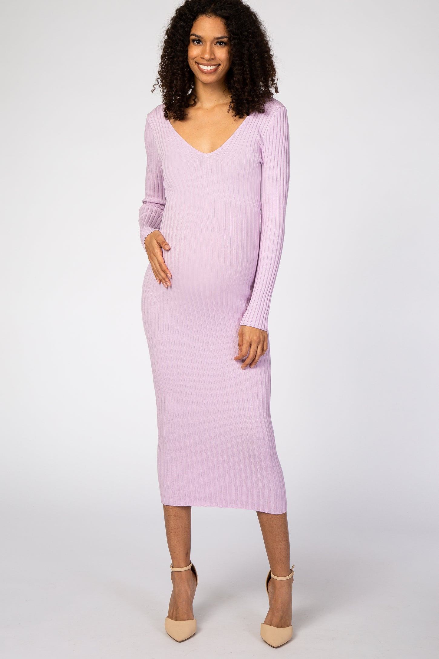 woman wearing a lavender ribbed long sleeve maternity dress and gently holding her baby bump
