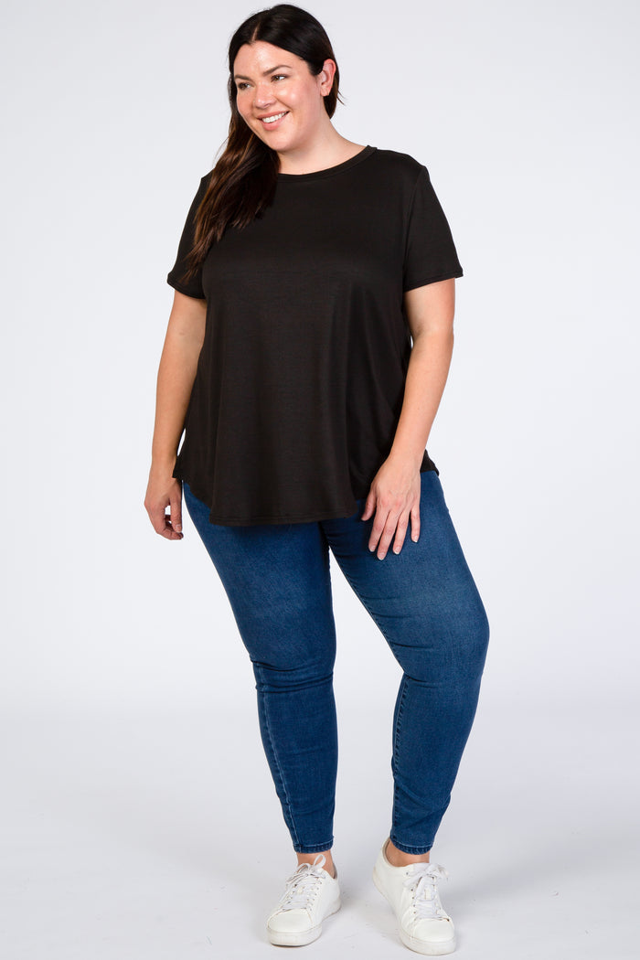 smiling woman wearing a black short sleeve tunic top and blue skinny jeans with white sneakers