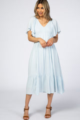 woman wearing a light blue midi dress with flutter sleeves and a tiered hem