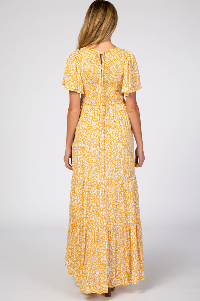 woman wearing a yellow floral maternity dress with short sleeves and a tiered skirt, seen from the back