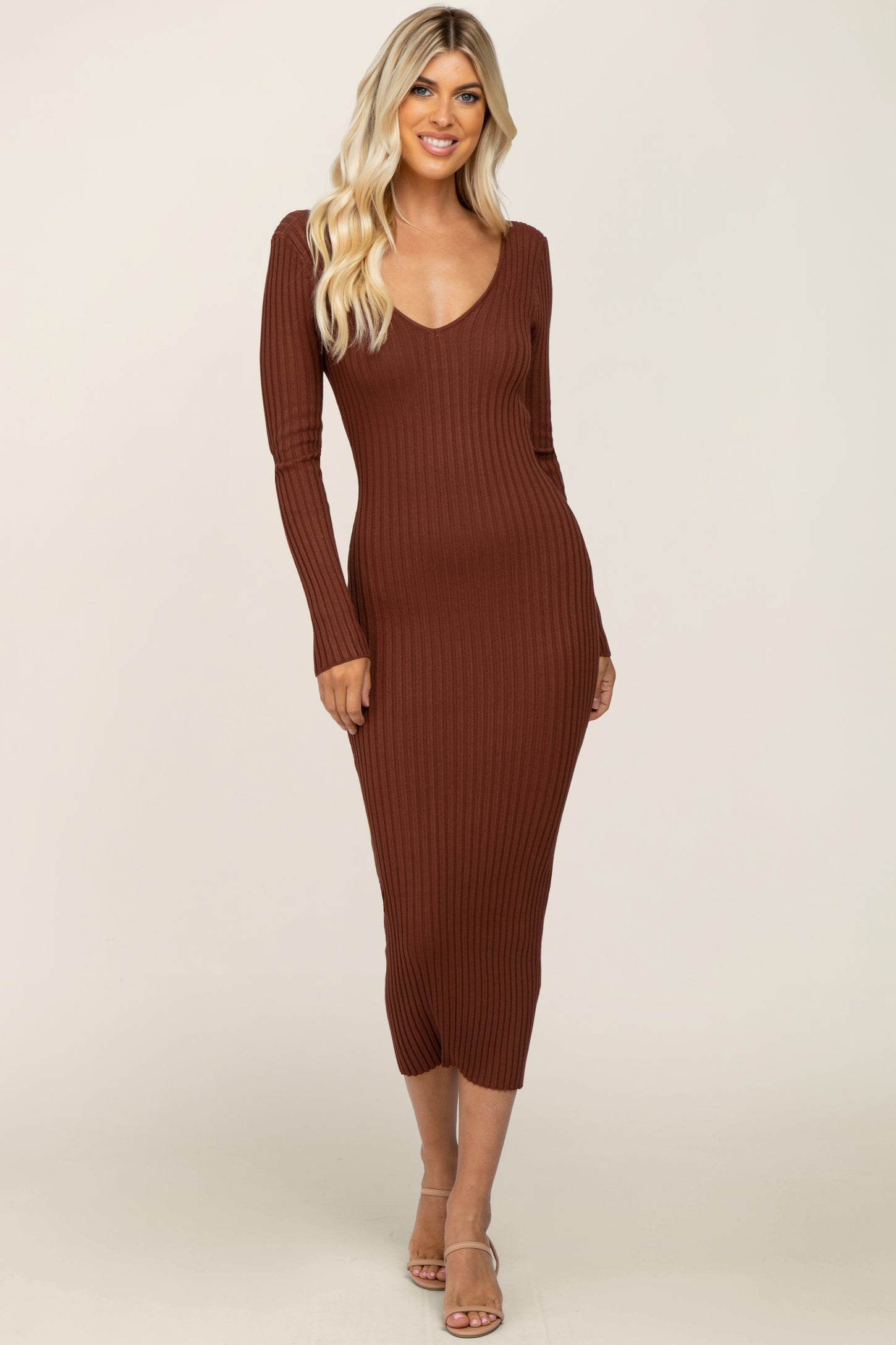 woman wearing a brown ribbed long sleeve midi dress with a v-neckline and a fitted silhouette