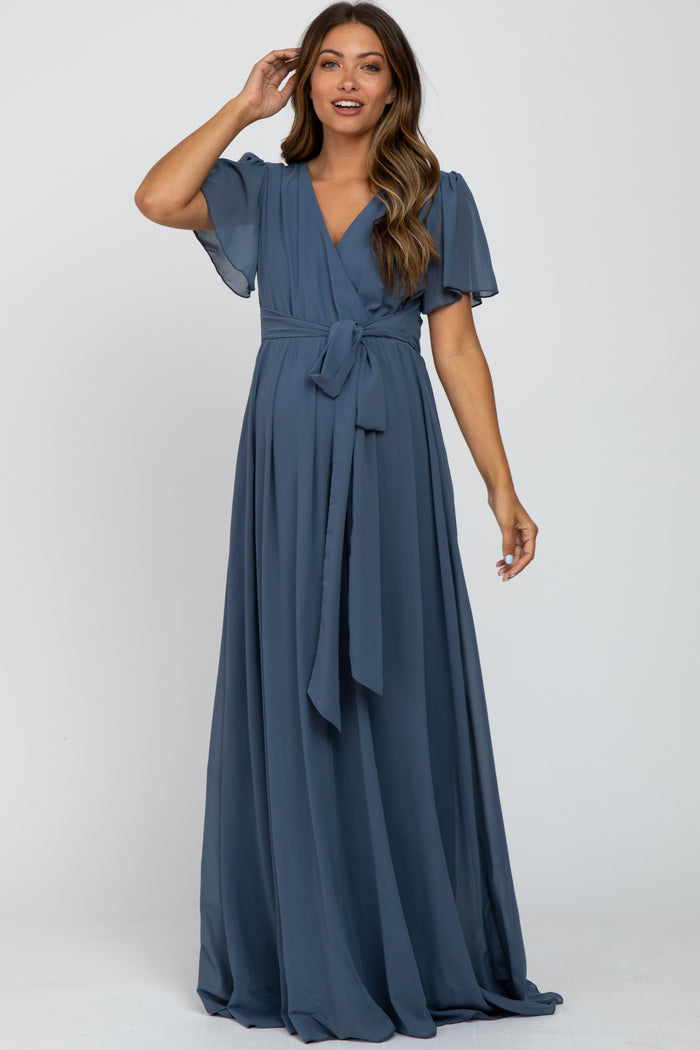 woman wearing a blue maternity wrap dress with flutter sleeves and a tie waist