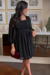 woman wearing a black smocked mini dress with balloon sleeves and a textured design, holding a burgundy clutch