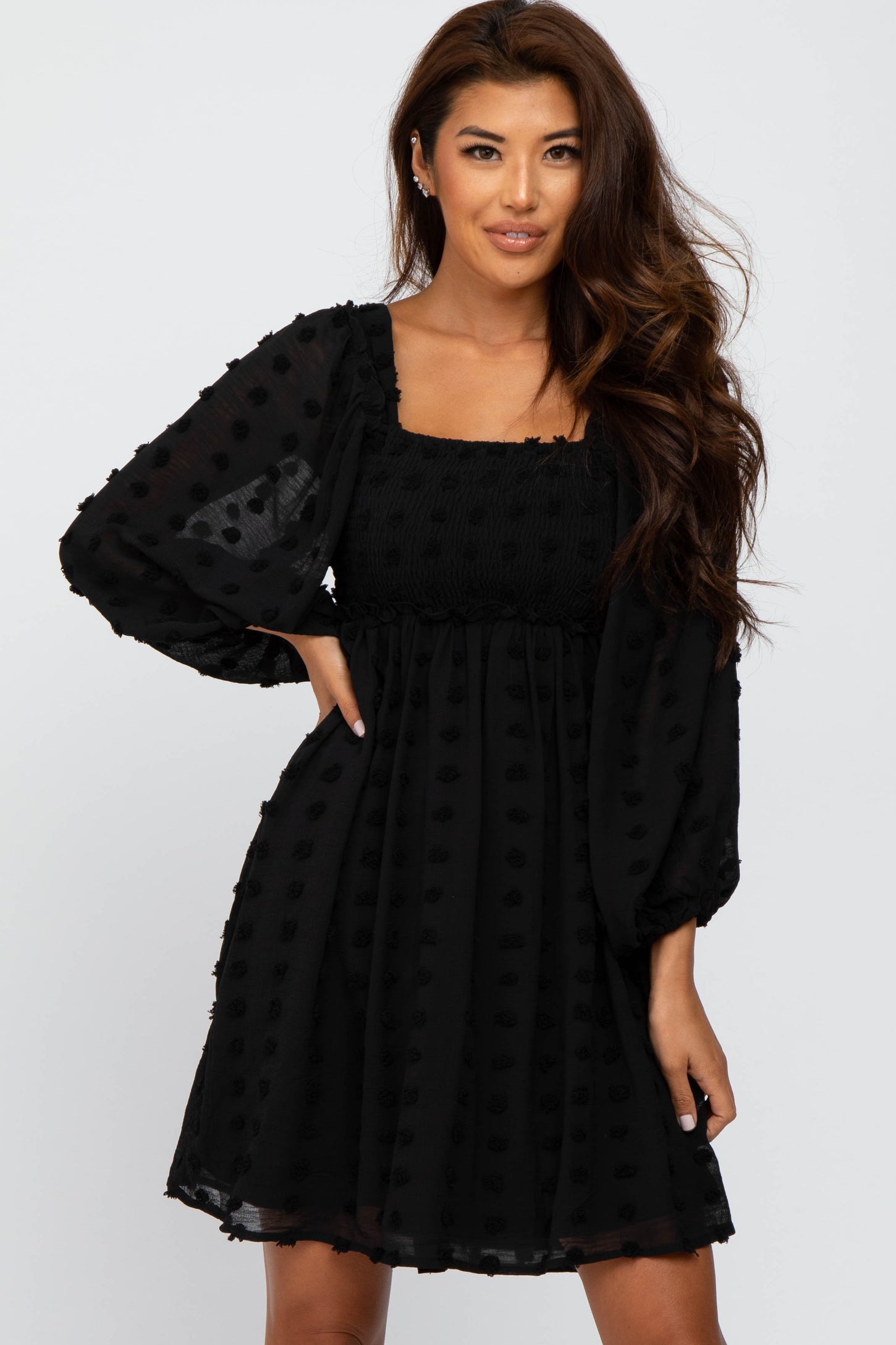 woman wearing a black puff sleeve mini dress with textured dots and a square neckline