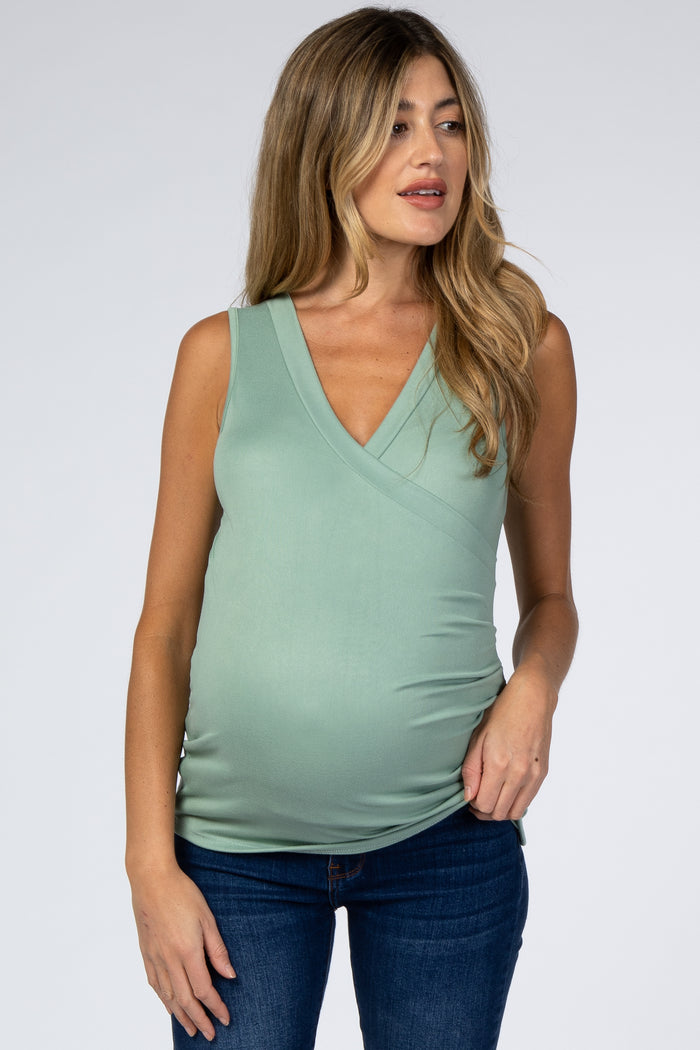 woman wearing a light green maternity sleeveless top with a v-neck and a visible baby bump