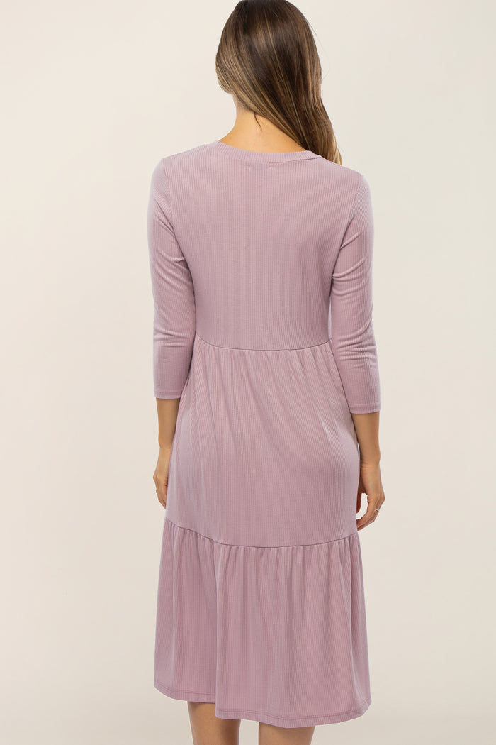 Back view of a woman wearing a mauve ribbed knit tiered midi dress with three-quarter sleeves