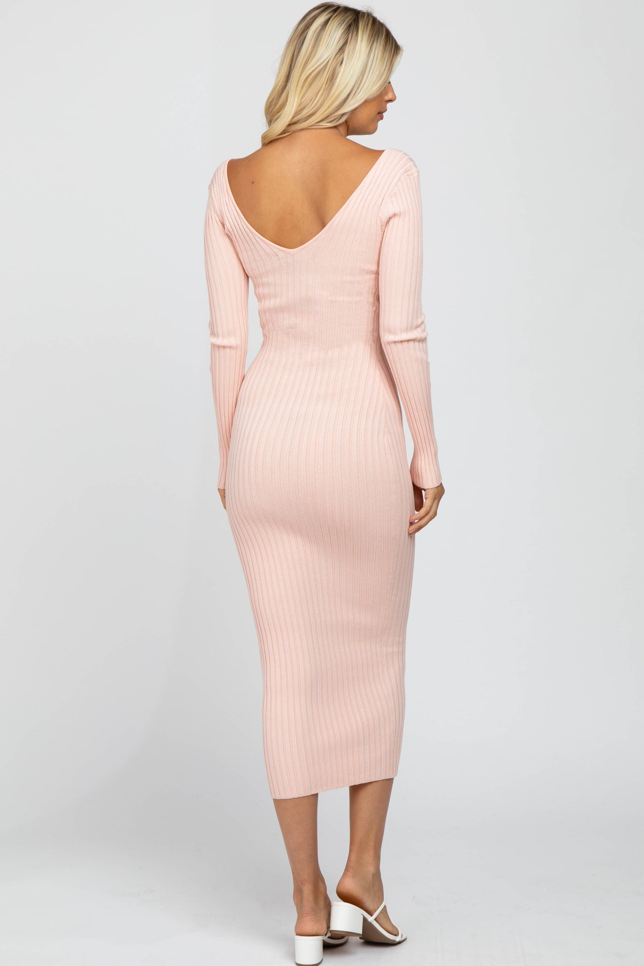 woman wearing a light pink ribbed midi dress with a deep v-back and long sleeves