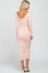 woman wearing a light pink ribbed midi dress with a deep v-back and long sleeves
