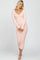 woman wearing a light pink ribbed long sleeve midi dress with a v-neckline and hugging silhouette