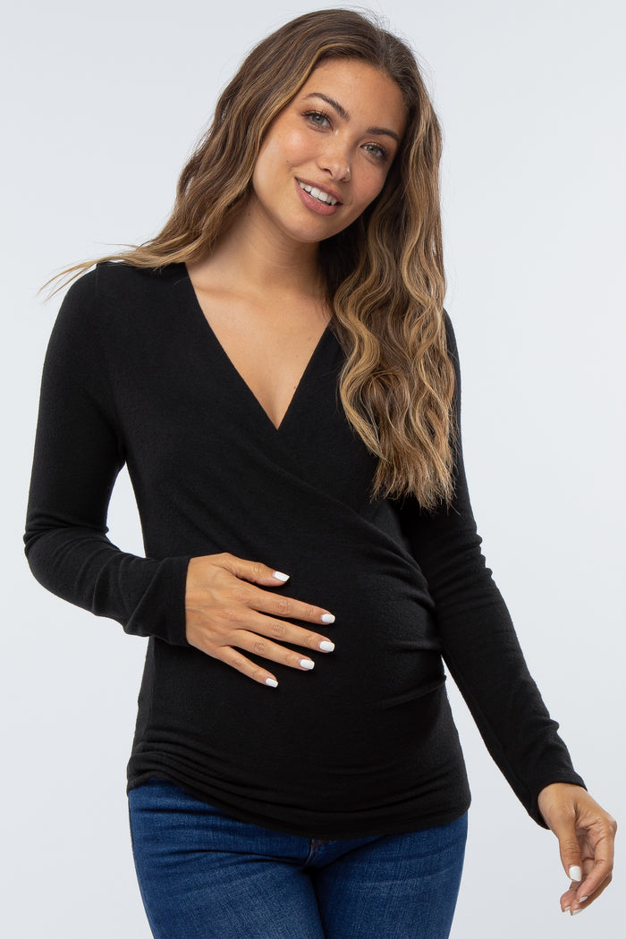woman wearing a black long sleeve maternity top and holding her baby bump