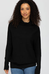woman wearing a black cowl neck sweater with long sleeves and relaxed fit, paired with light blue jeans