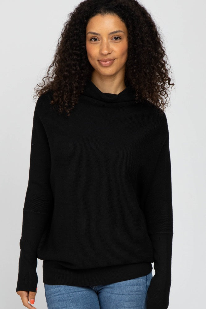 woman wearing a black cowl neck sweater with long sleeves and relaxed fit, paired with light blue jeans