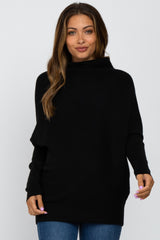 woman wearing a black oversized maternity sweater with a high neckline and long sleeves