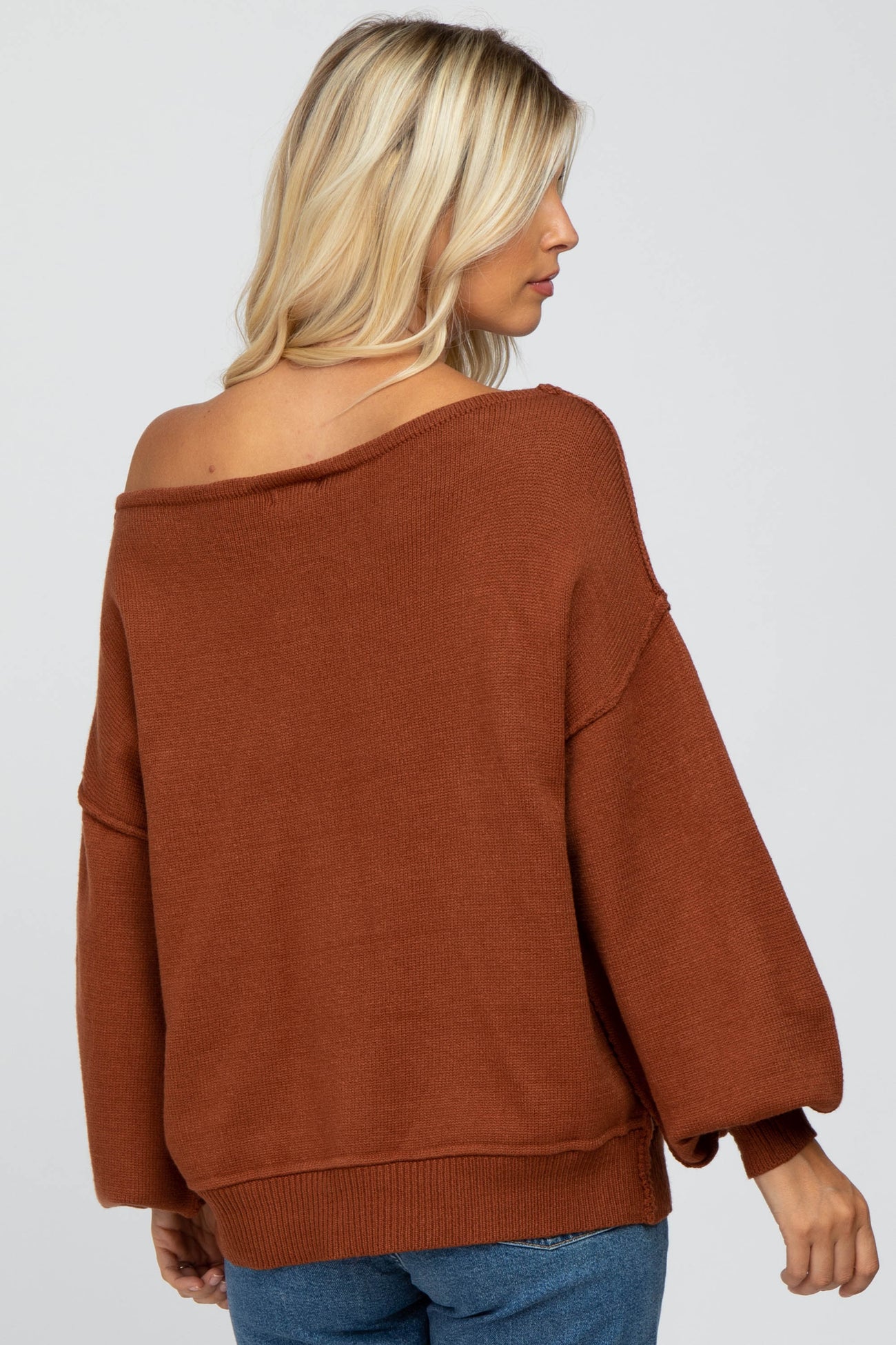 woman wearing a rust-colored off-the-shoulder oversized sweater with balloon sleeves