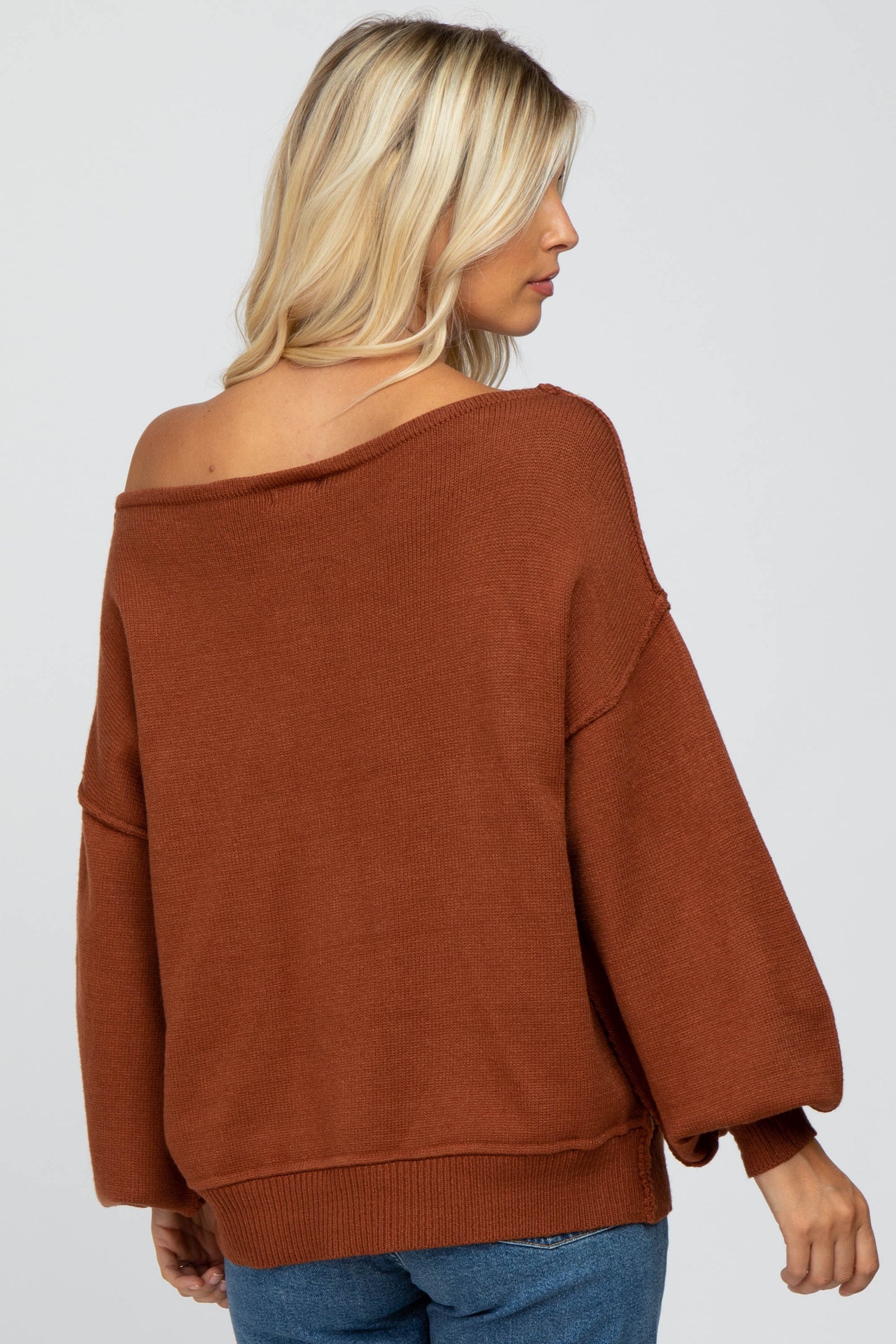 woman wearing a rust-colored off-the-shoulder oversized sweater with balloon sleeves
