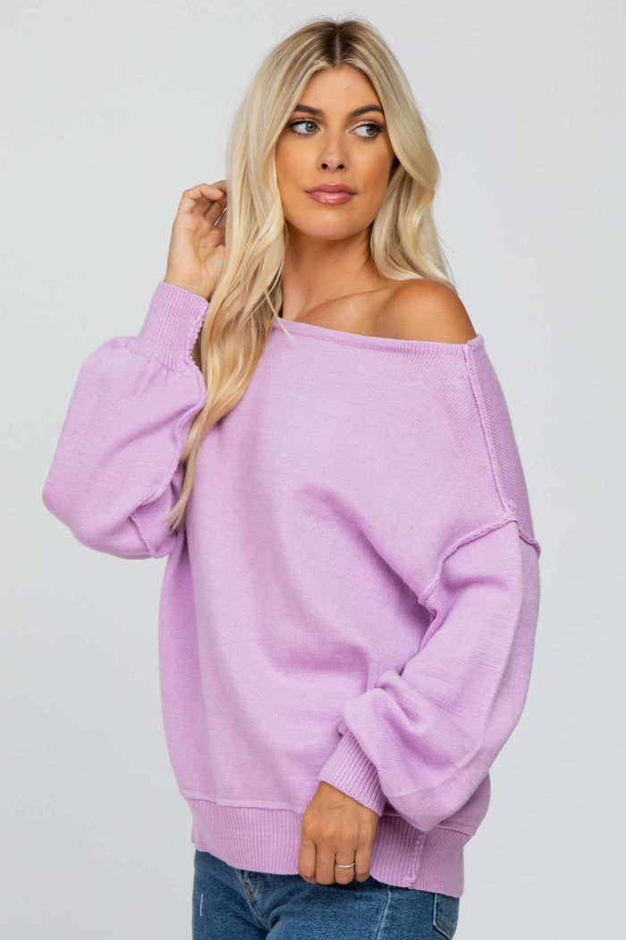 woman with blonde hair wearing a light purple off-the-shoulder knit sweater and blue jeans