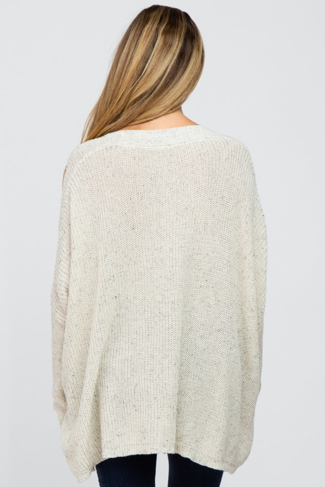 woman wearing a cream oversized maternity knit sweater, showing the back view with a relaxed fit