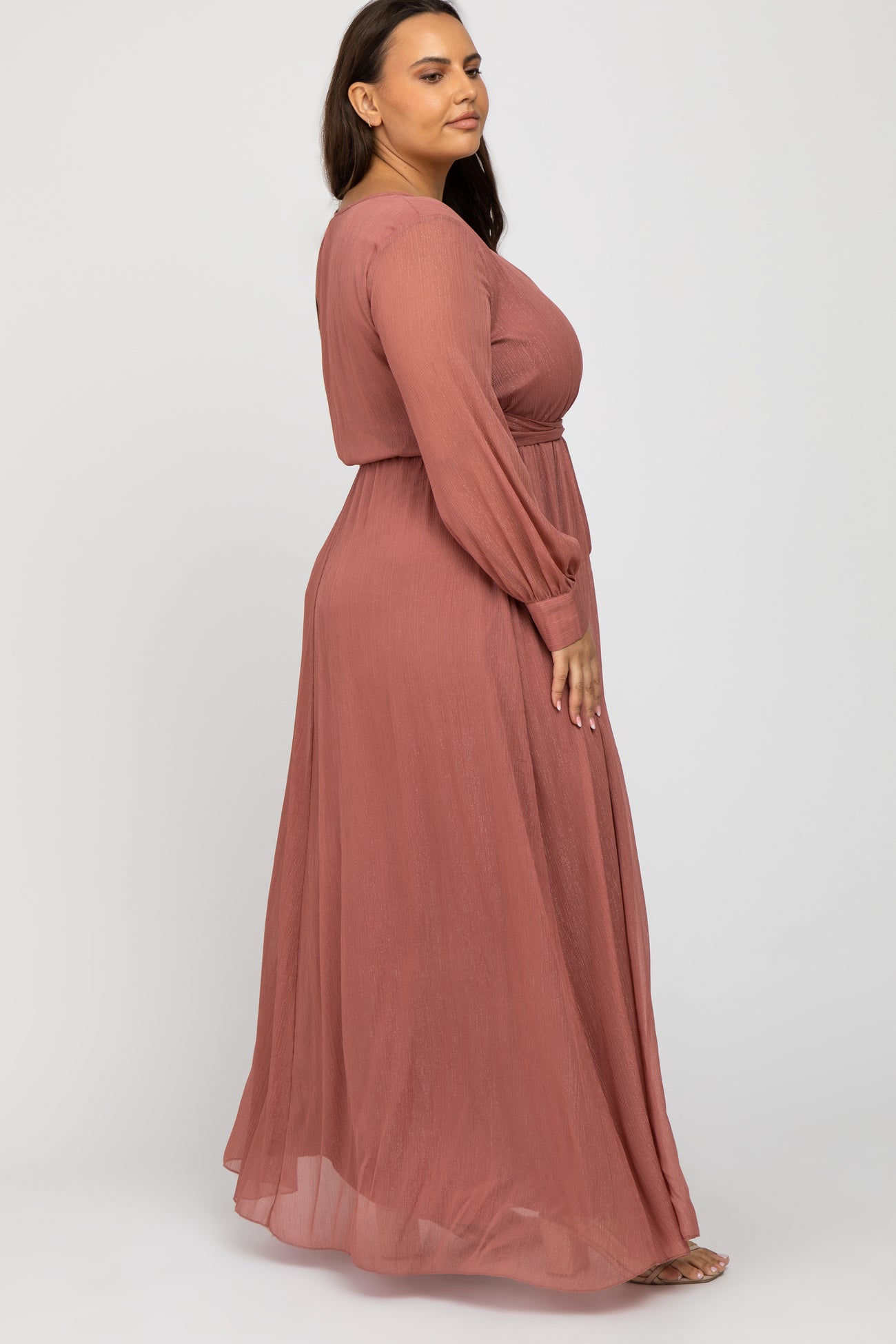woman wearing a rose pink long sleeve maxi dress with a side view showing flowy silhouette and gathered waistline