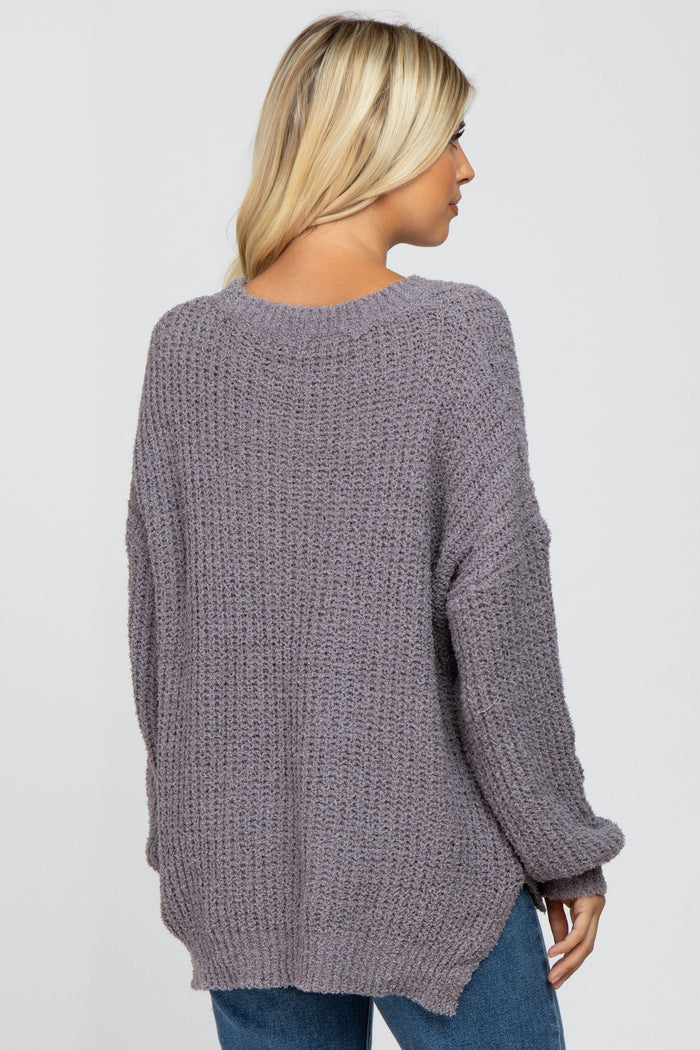 back view of a woman wearing a mauve oversized popcorn knit sweater and blue jeans