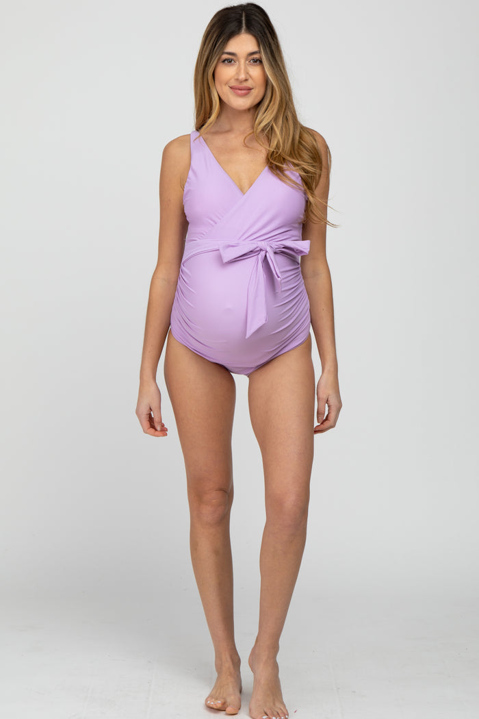 woman wearing a light lavender maternity swimsuit with a wrap design and a bow detail, showing her baby bump