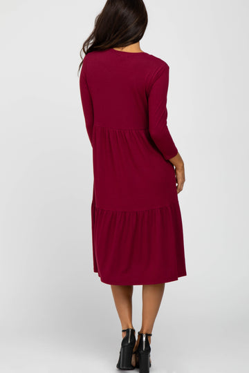 woman wearing a long burgundy tiered dress with three-quarter sleeves seen from the back