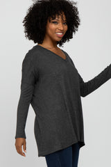 woman wearing a dark gray long sleeve v-neck top and smiling while posing with her hand raised