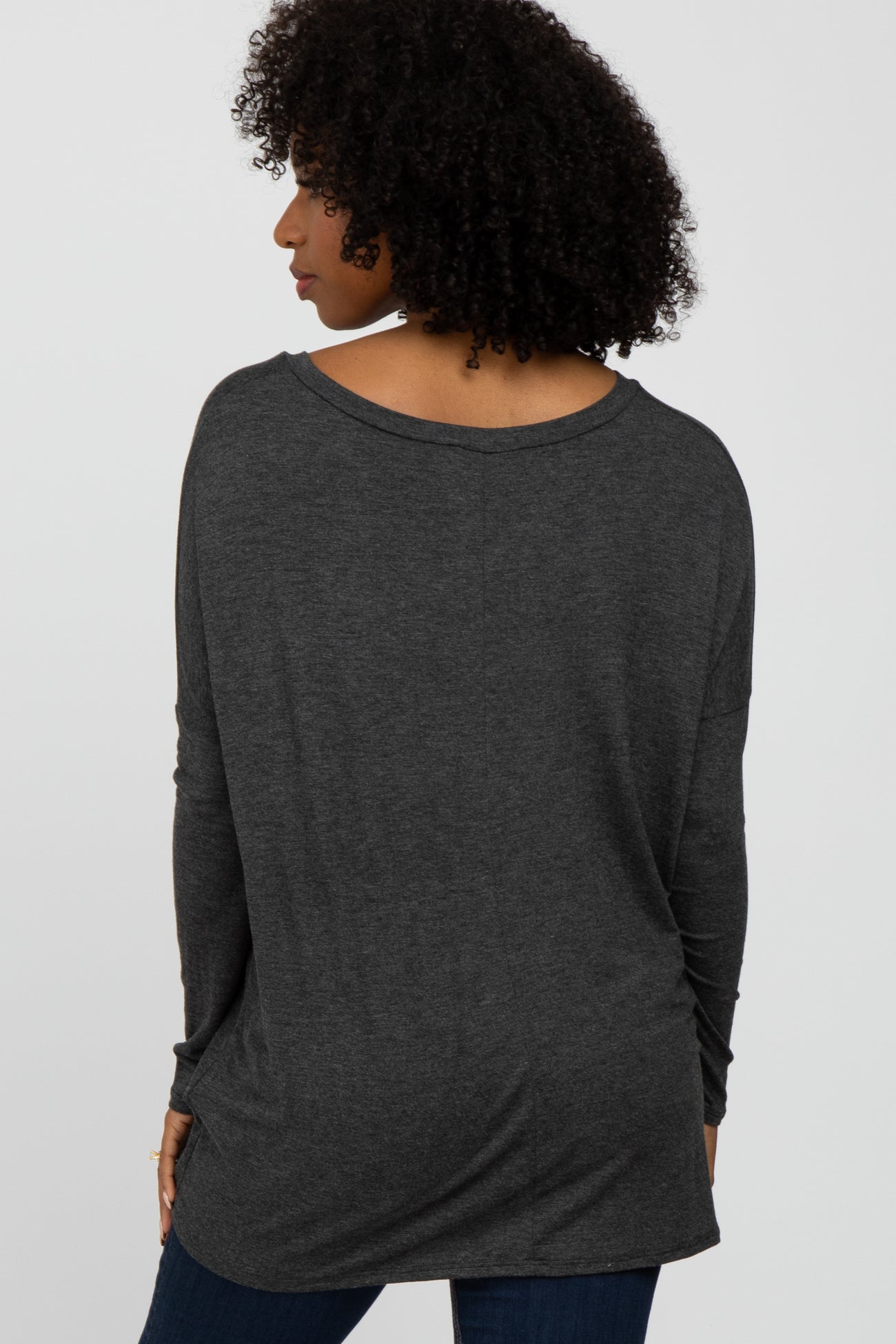 woman wearing a dark gray oversized long sleeve top, viewing from the back, styled with loose fit and dropped shoulders