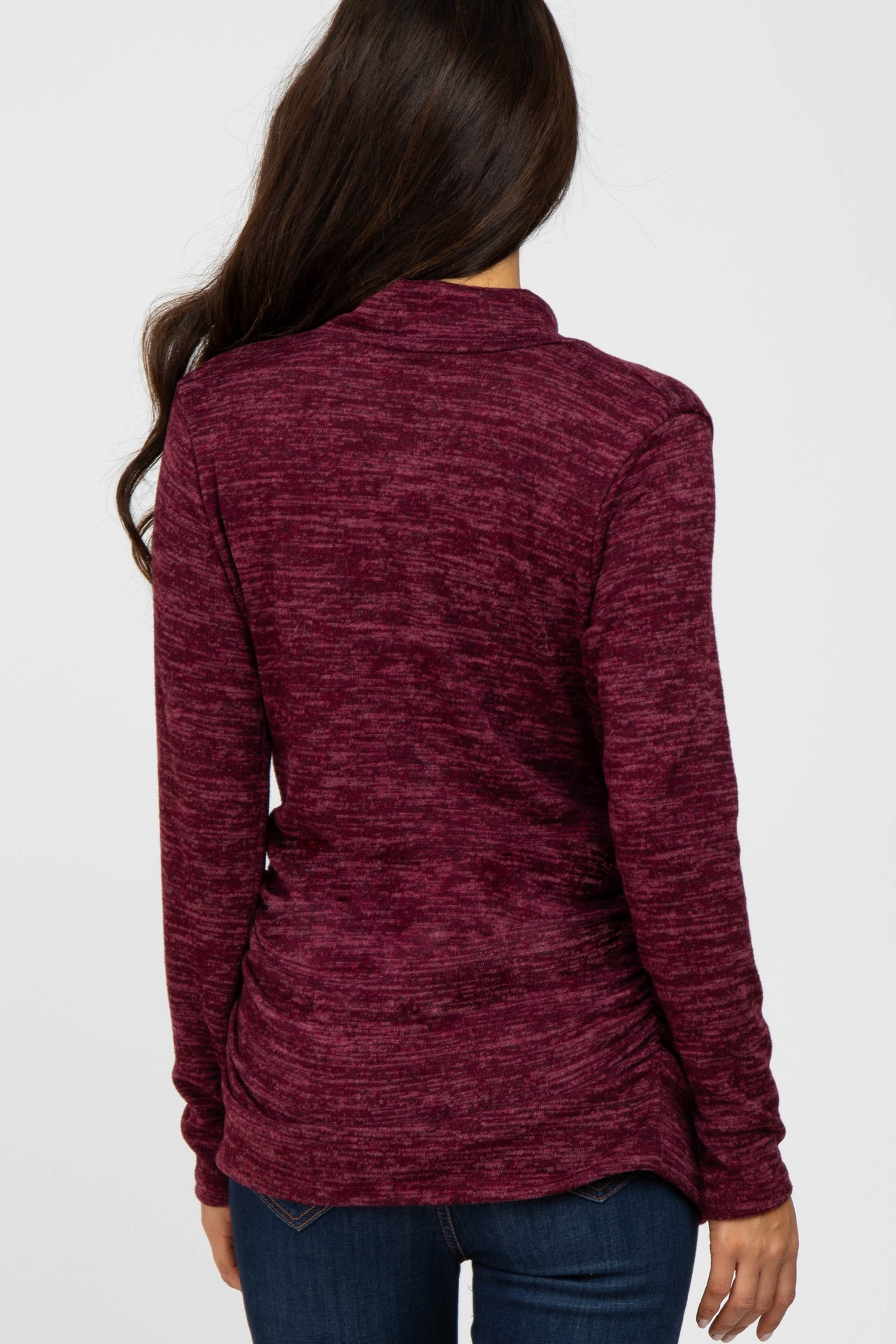 woman wearing a burgundy long sleeve top with a textured finish and gathered back detail