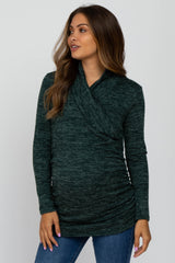woman wearing a dark green long sleeve maternity top with a wrap design and ruching, showing her baby bump