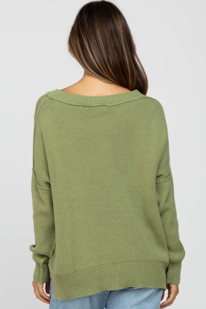 woman wearing a loose-fitting olive green maternity sweater, shown from the back