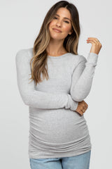 woman wearing a light grey long sleeve maternity top with ruching, showcasing a visible baby bump