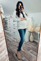 pregnant woman in grey long sleeve maternity top and blue jeans taking mirror selfie in a walk-in closet