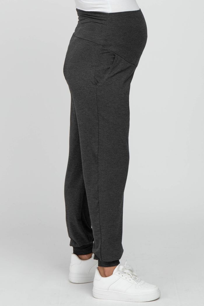 woman wearing gray maternity joggers with a waistband designed for a baby bump
