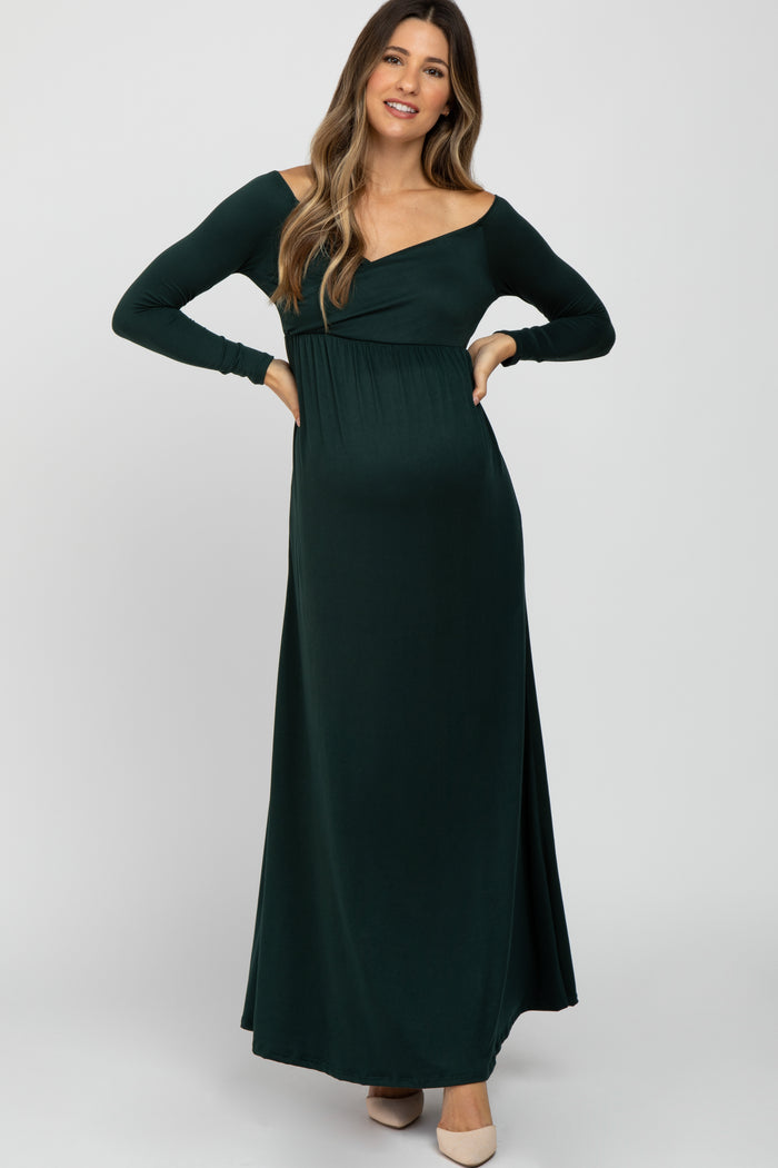 woman wearing a dark green off-shoulder maternity dress with long sleeves and a visible baby bump