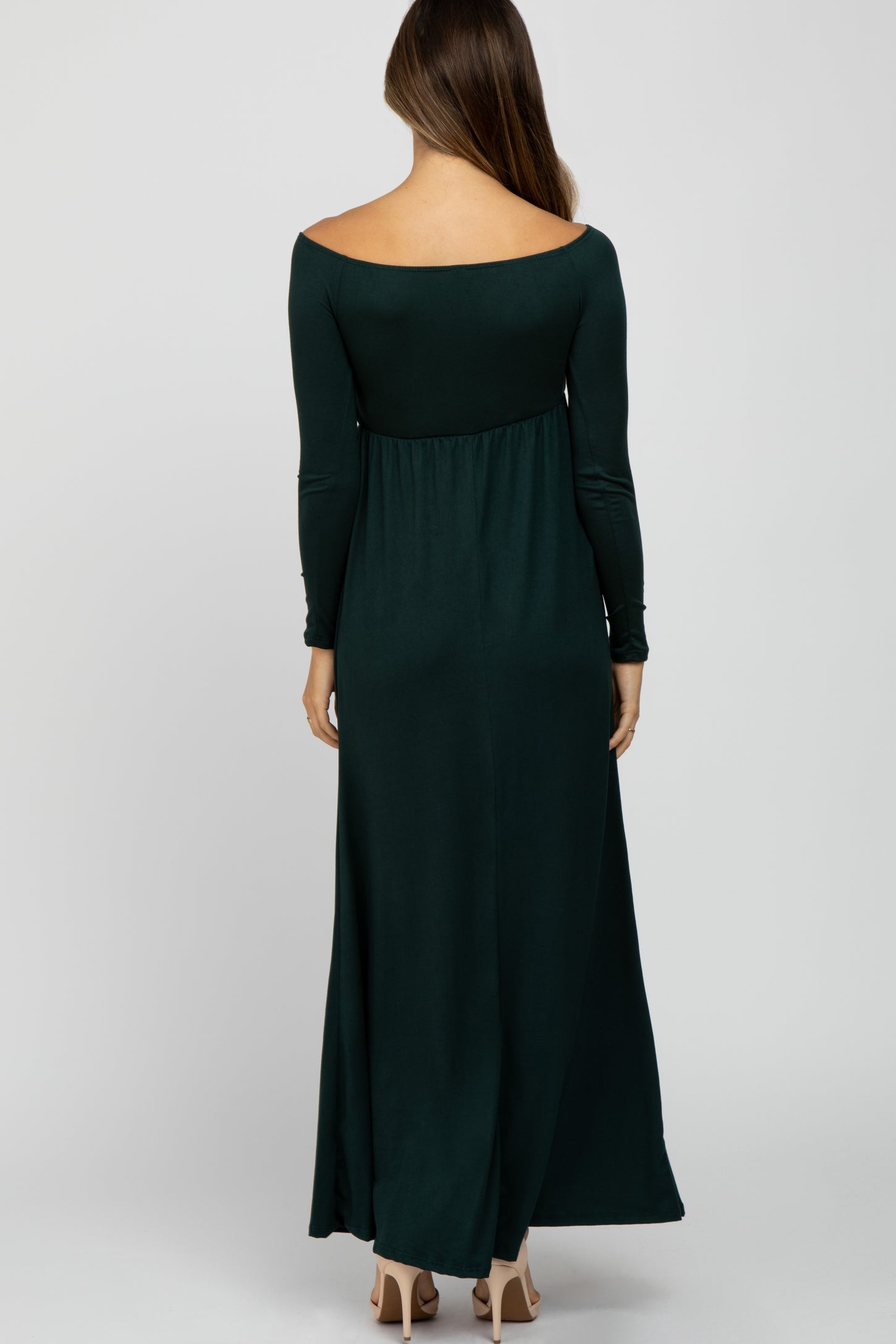 woman wearing a dark green off-shoulder maternity maxi dress with long sleeves, showing a flowing silhouette from the back