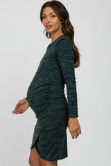 woman wearing a dark green long sleeve maternity dress with a side ruching detail and a visible baby bump