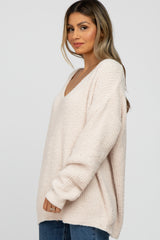 woman wearing a light pink oversized v-neck sweater with long sleeves and relaxed fit