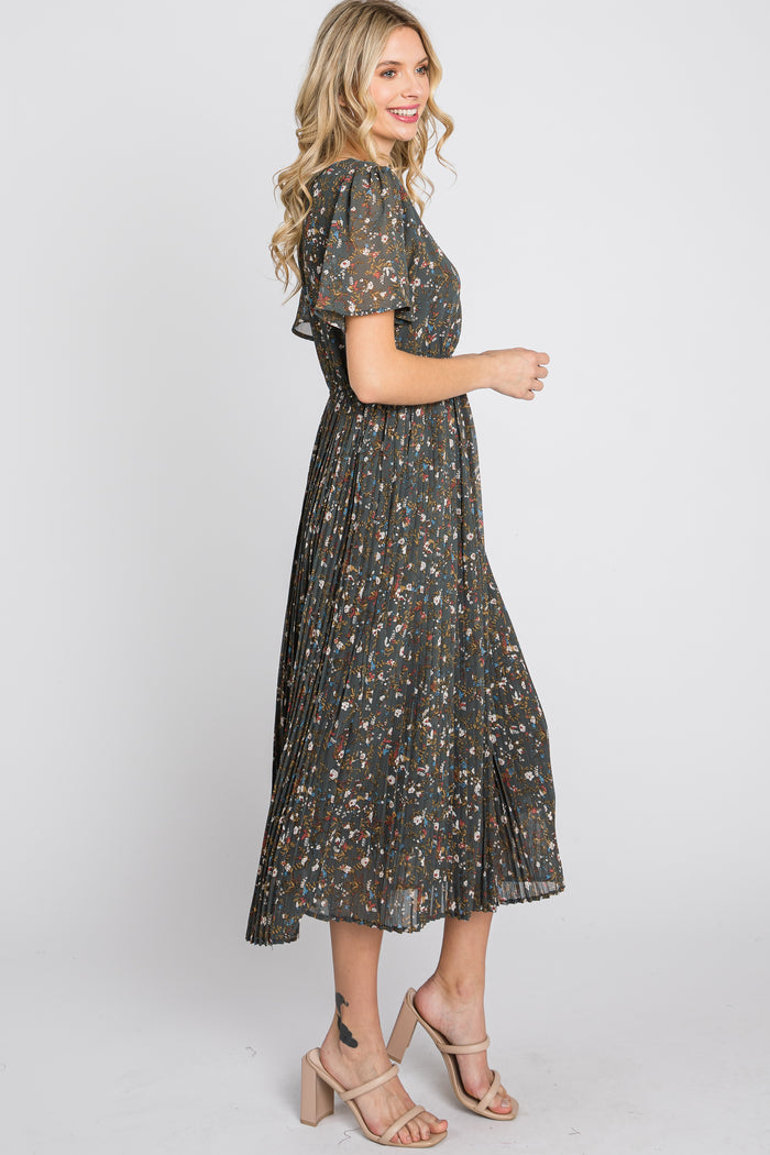 woman wearing a dark floral midi dress with short sleeves and pleated skirt, standing sideways with a smile
