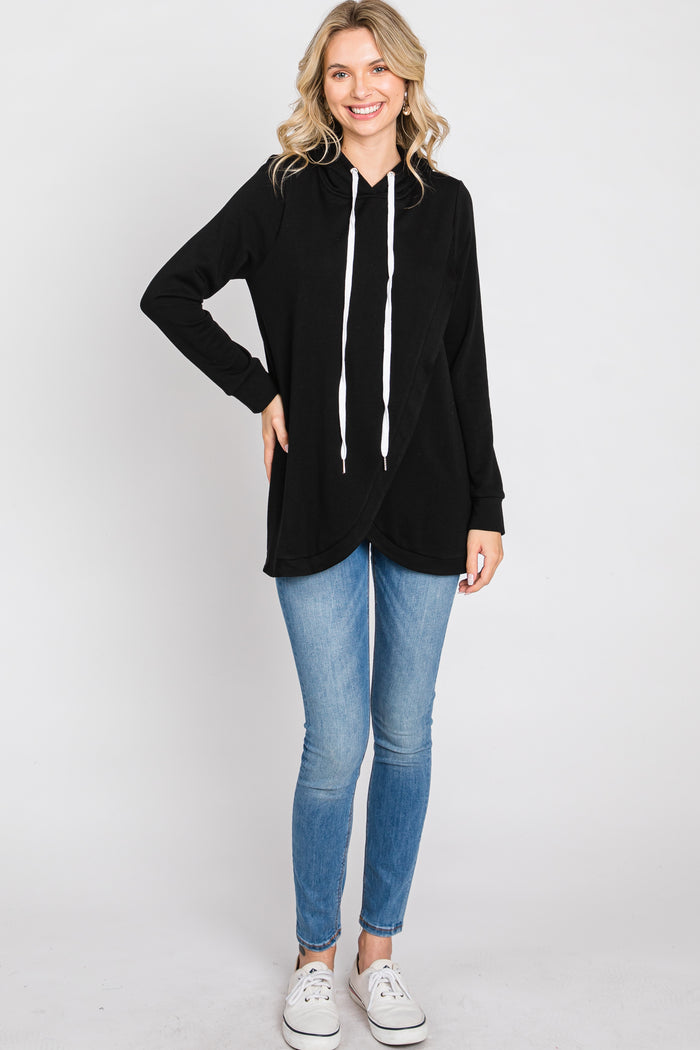 woman wearing a black long sleeve hooded tunic top with a white drawstring and blue skinny jeans