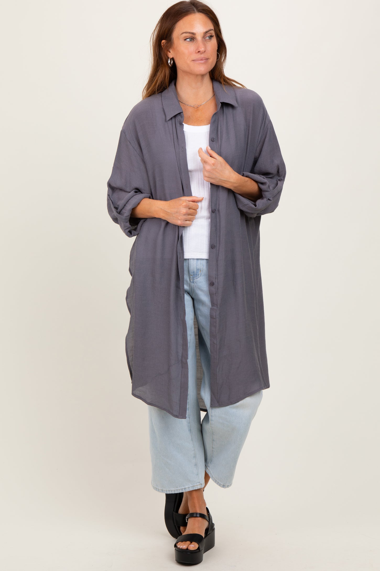 woman wearing a gray oversized button-up shirt and light blue wide-leg jeans with black platform sandals