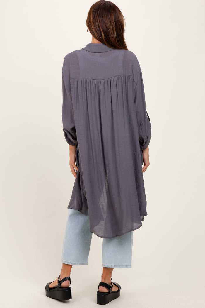 woman wearing a long gray button-up shirt with a flowy back, paired with light blue wide-leg jeans and black sandals